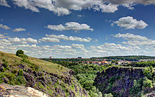 Divoká Šárka, site naturel à l'ouest de Prague, incorporé au périmètre municipal. Paysage verdoyant mais très accidenté, au loin des constructions.
